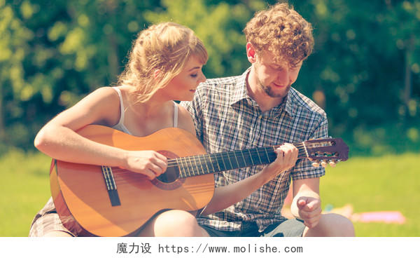 年轻的夫妇游客在露营时弹奏吉他